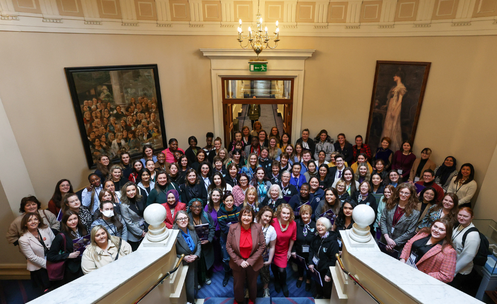 A group photo of women from across Ireland standing in Dáil Éireann, looking up to the camera.