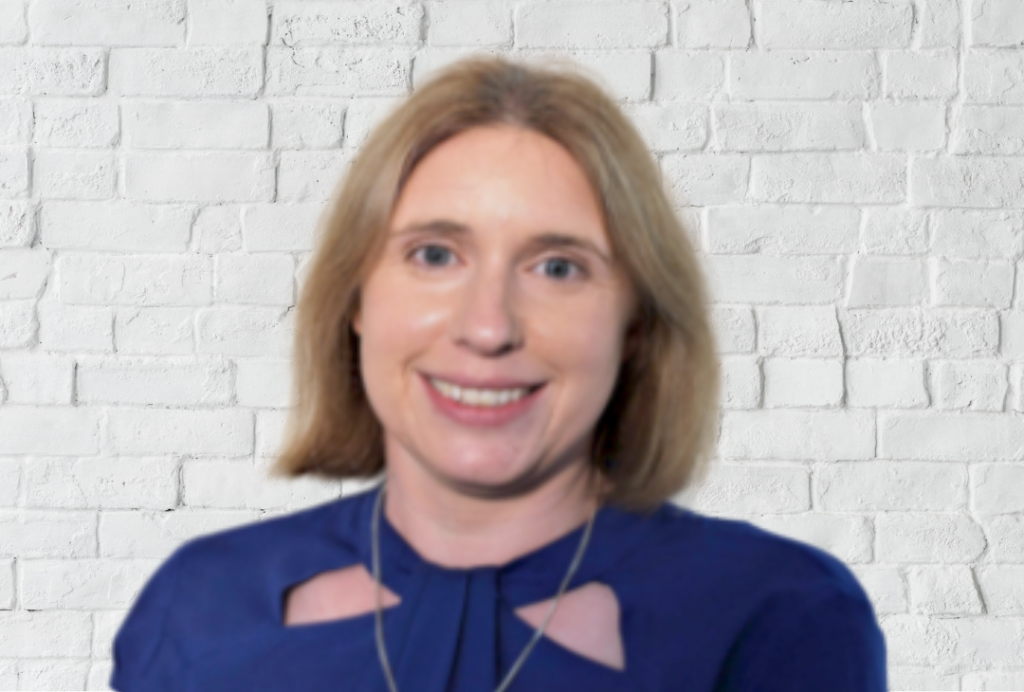 Woman with short blonde hair smiles at camera.