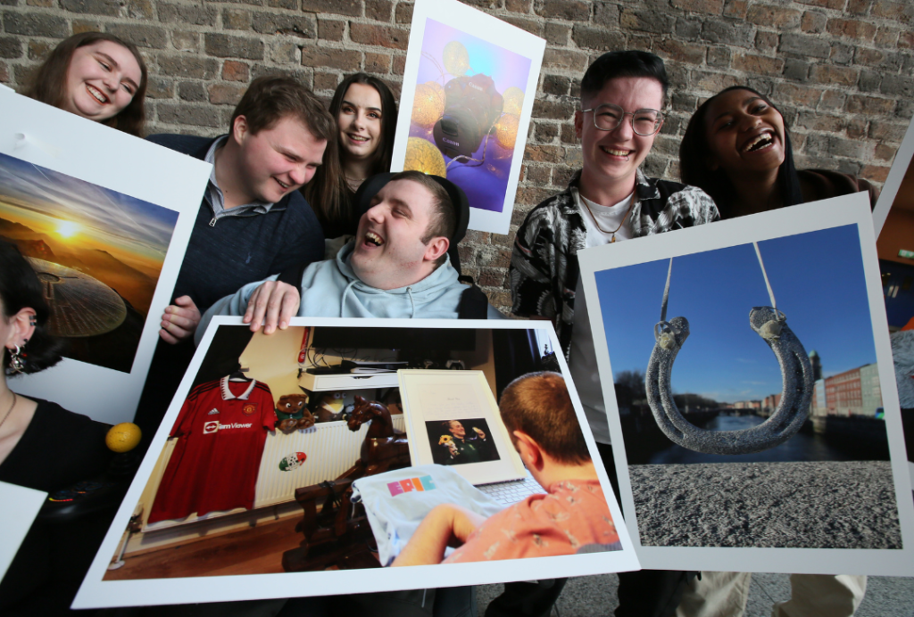 Members of our Youth Council holding large photographs and laughing.