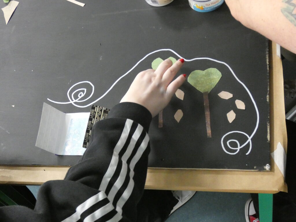 A hand sticking down a piece of paper onto a black board.