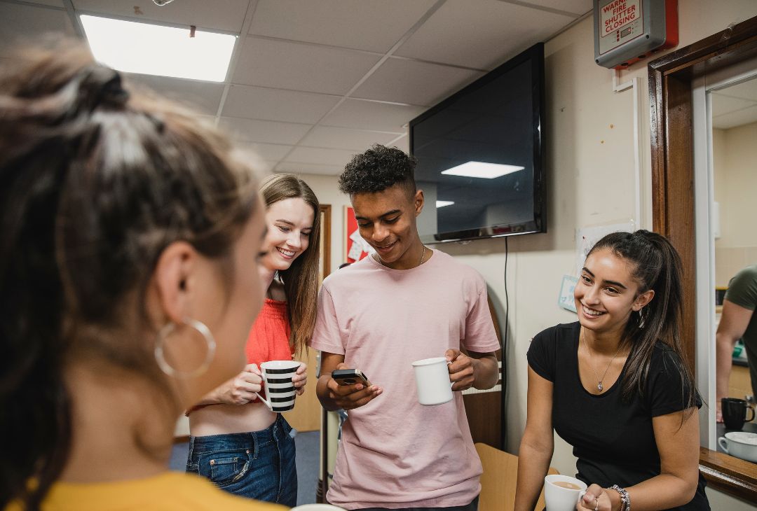 Group of young people drinking tea and smiling.