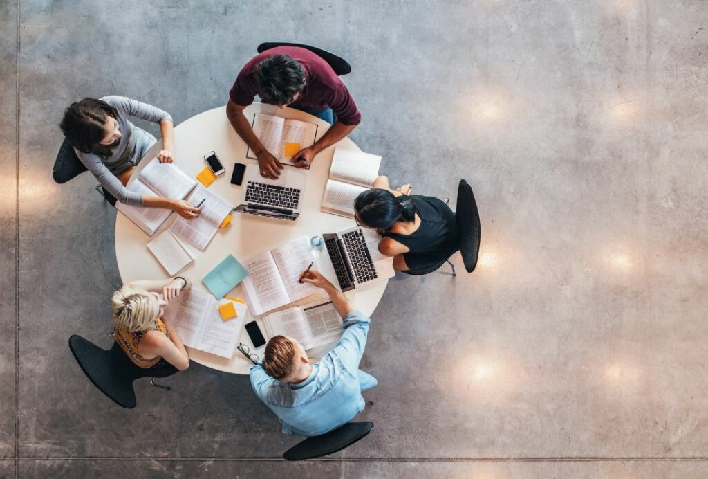 Group of college students sat around a table from top down view.