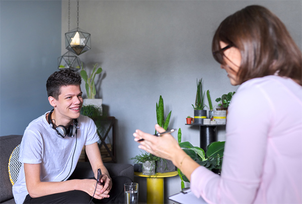 Image of a woman speaking to a young man across a table.